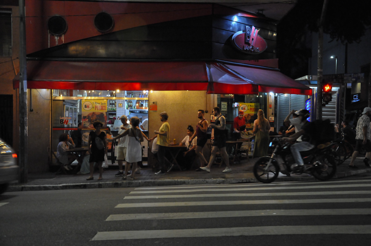 Rua Augusta movimentada, pessoas andando e sentadas no bar
