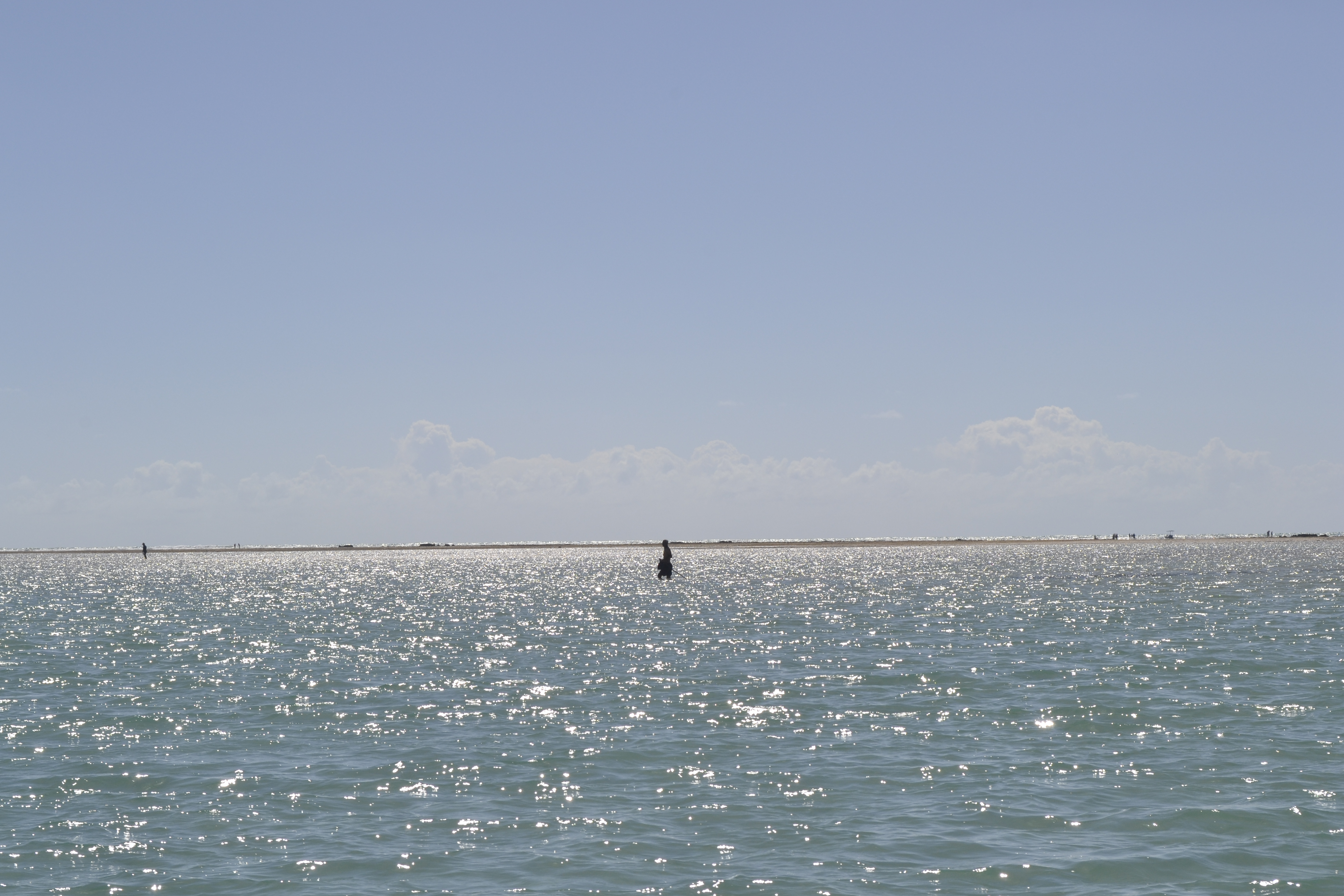 Homem andando em águas rasas do mar de São Miguel dos Milagres, em Alagoas