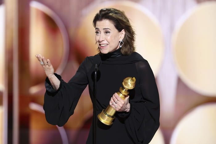 Fernanda Torres segurando o prêmio do Globo de Ouro enquanto discursa após vitória pelo filme "Ainda Estou Aqui"