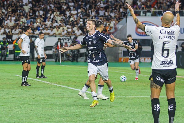 Jogador do Remo comemorando gol enquanto os do Corinthians lamentam.