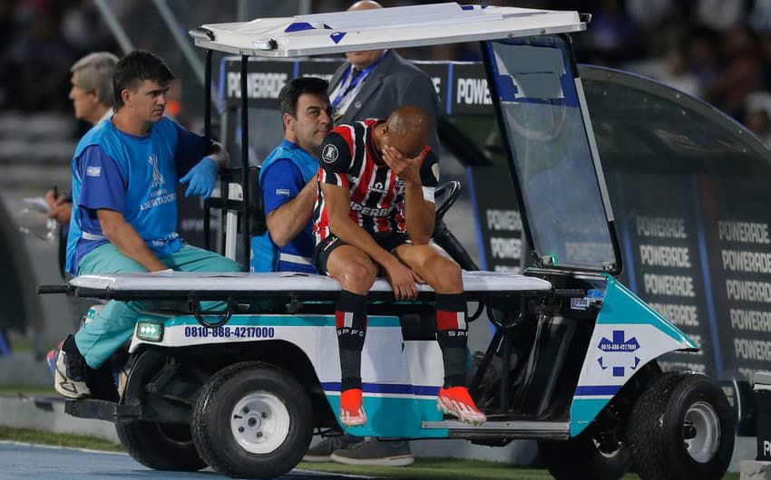 Jogador Lucas Moura sendo levado para fora dos gramados em um carro médico.
