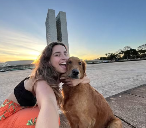Ana Uchoa com sua cachorra Isis na frente de um monumento em Brasília
