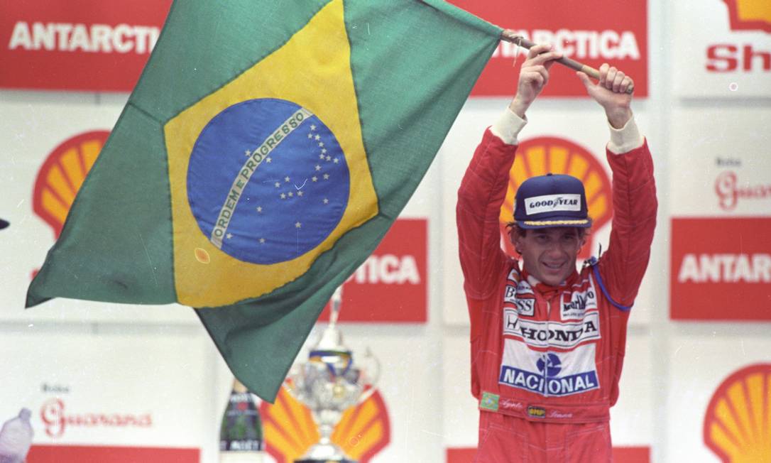 A primeira vitória de Senna em Interlagos, após uma corrida em condições extremas, levantando com dificuldade a bandeira brasileira – Foto: Fernando Pereira