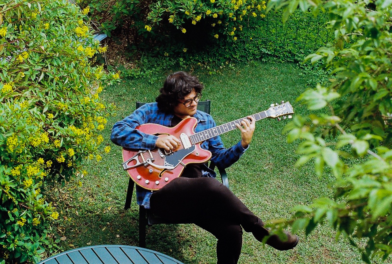 Gabriel Buchmann no jardim tocando guitarra