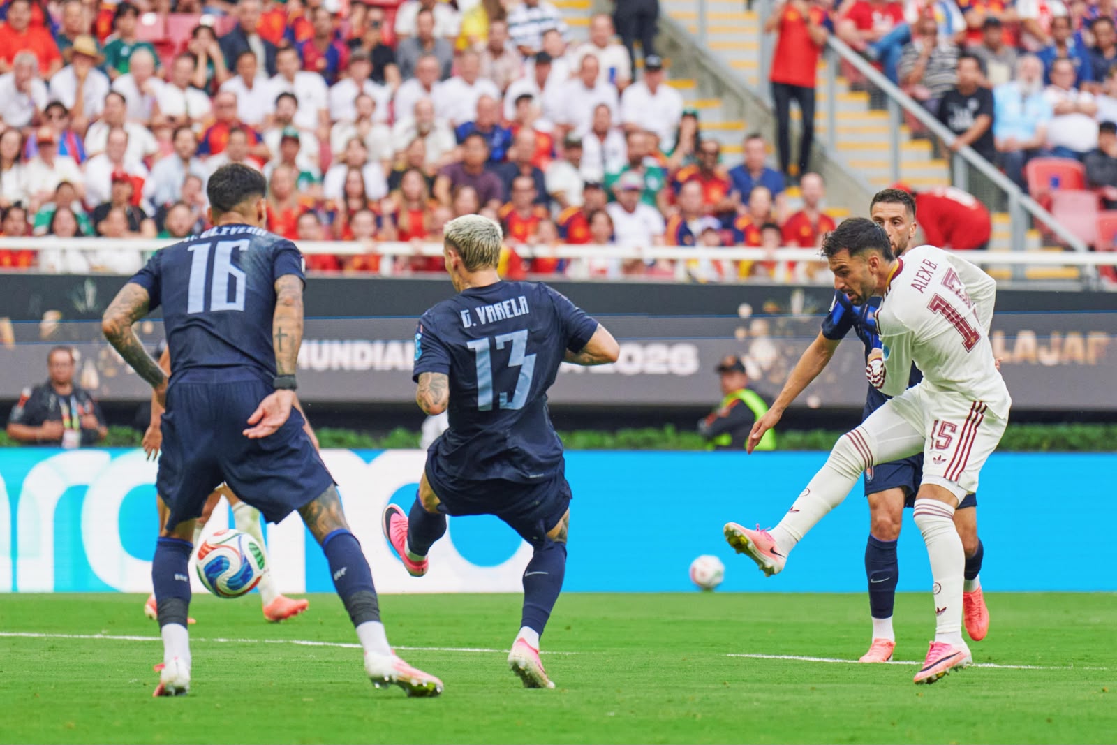 A imagem mostra Baena chutando a bola e defensores uruguaios tentando defender