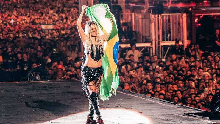 Karol G segurando a bandeira do Brasil durante show no Rock In Rio