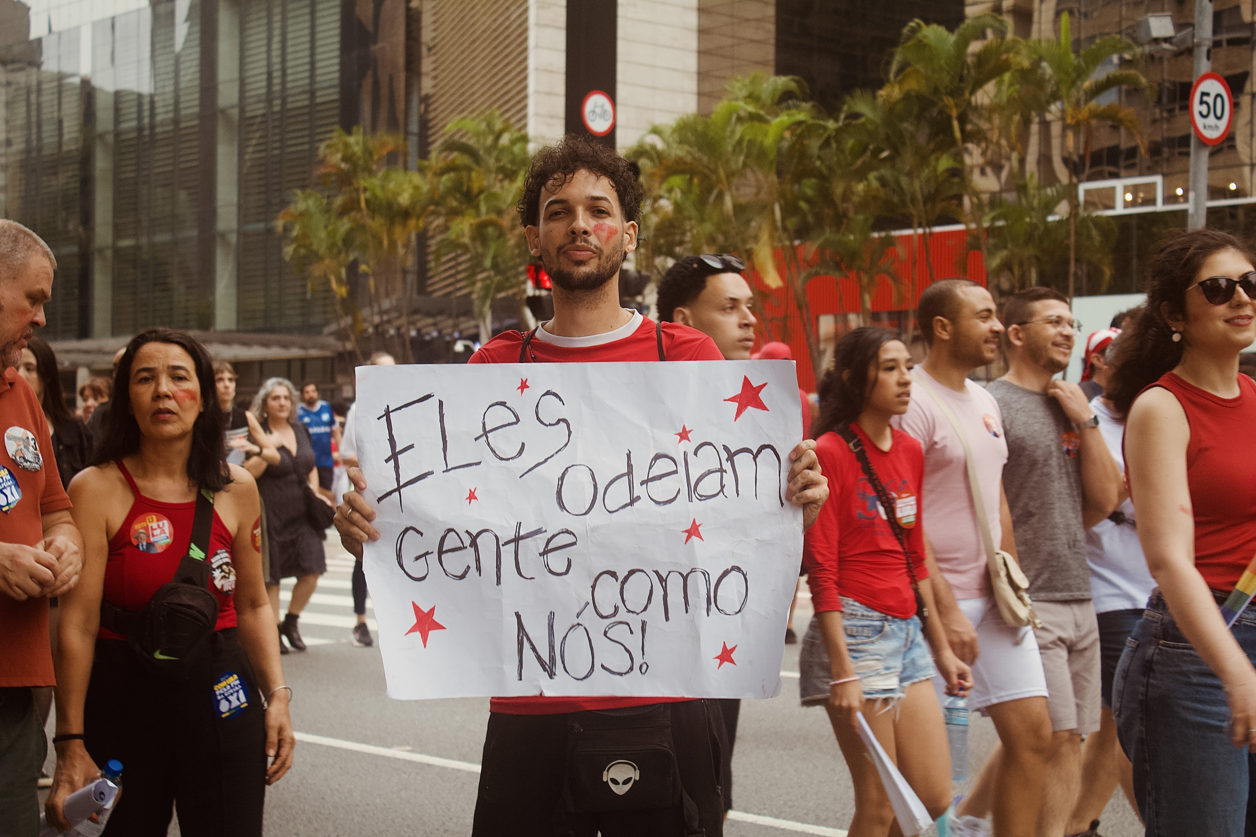 Manifestante segura cartaz escrito "eles odeiam gente como nós"
