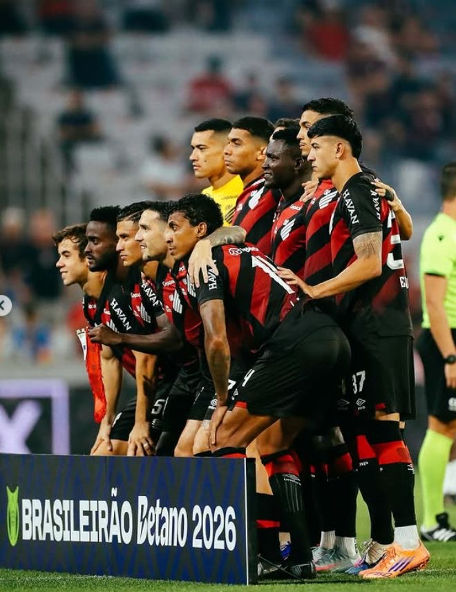 A imagem mostra os jogadores do Athletico-PR posando para a foto da partida. Logo em baixo, há uma placa com os dizeres Brasileirão Betano 2026 