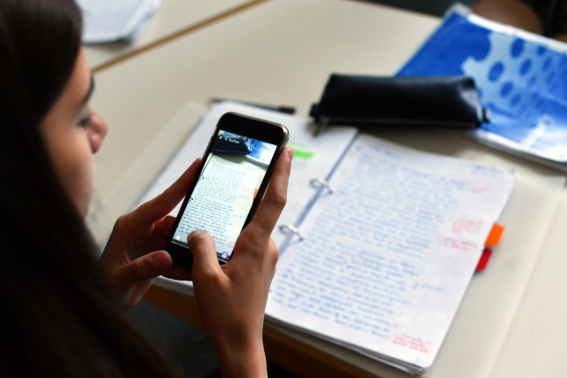 Estudante com um celular em sala de aula