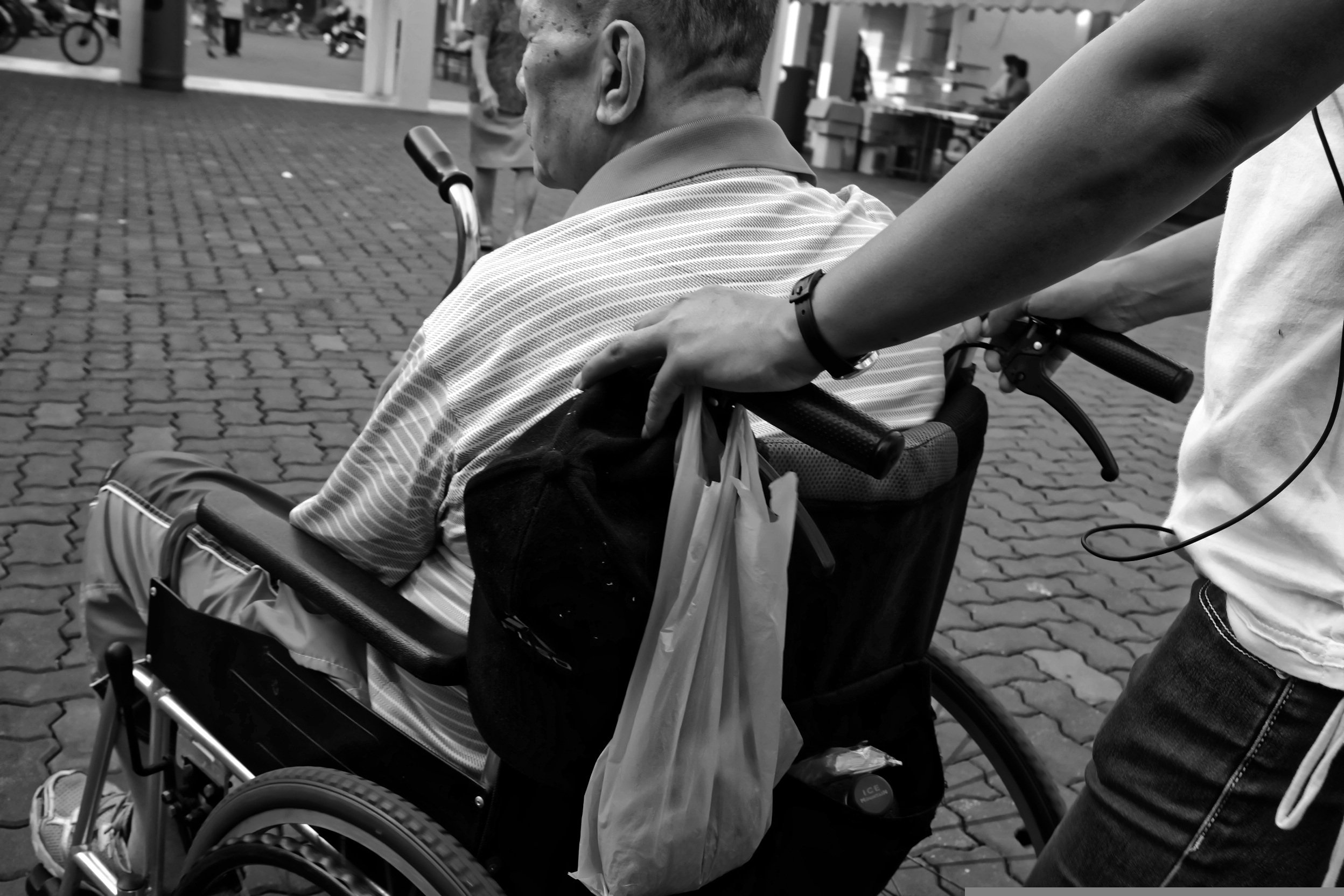Profissional auxiliando a mobilidade de um idoso que necessita de cuidados.