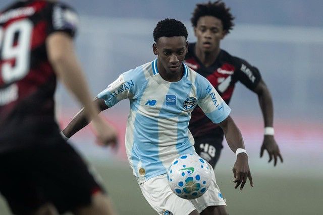 A imagem mostra o jogador Gabriel Mec, do Grêmio com a bola, cercado por dois jogadores do CAP.