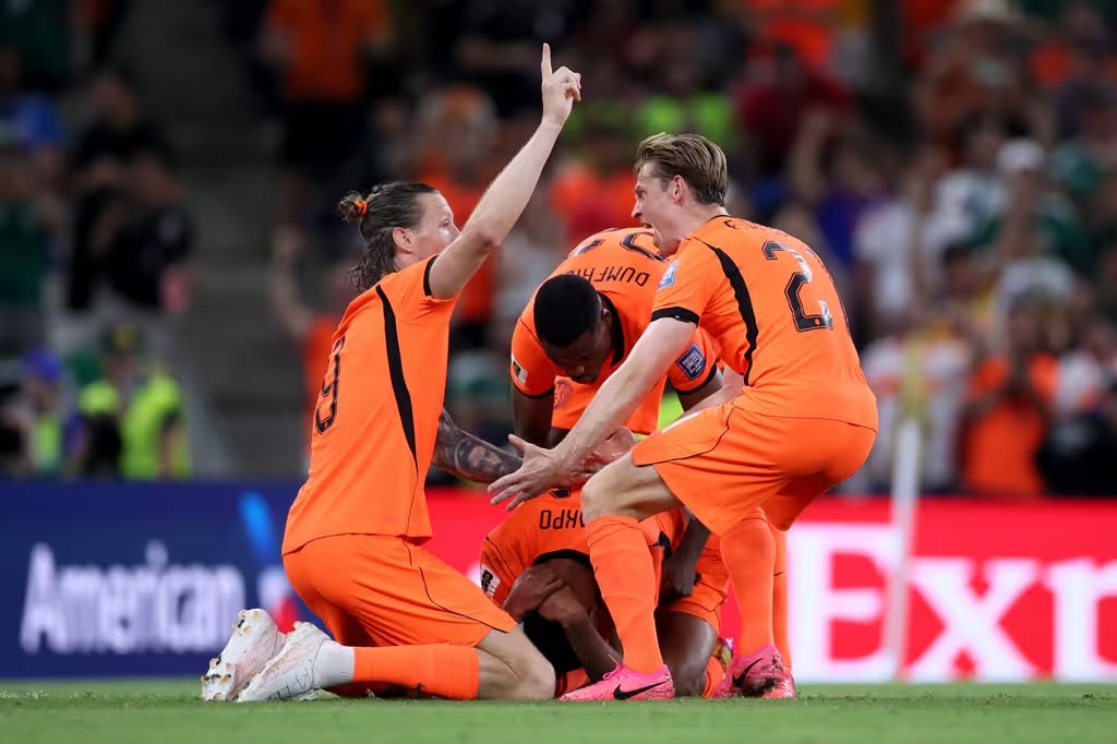A imagem mostra Gakpo, da Holanda ajoelhado de cabeça baixa. Em volta, De Jong e Weghorst comemoram o gol junto com ele