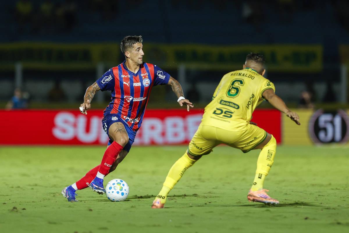 A imagem mostra Cristian Oliveira, do Bahia, correndo com a bola, enquanto Reinado, do Mirassol, tenta impedir.