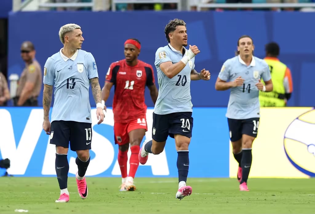 A imagem mostra três jogadores uruguaios andando em campo 