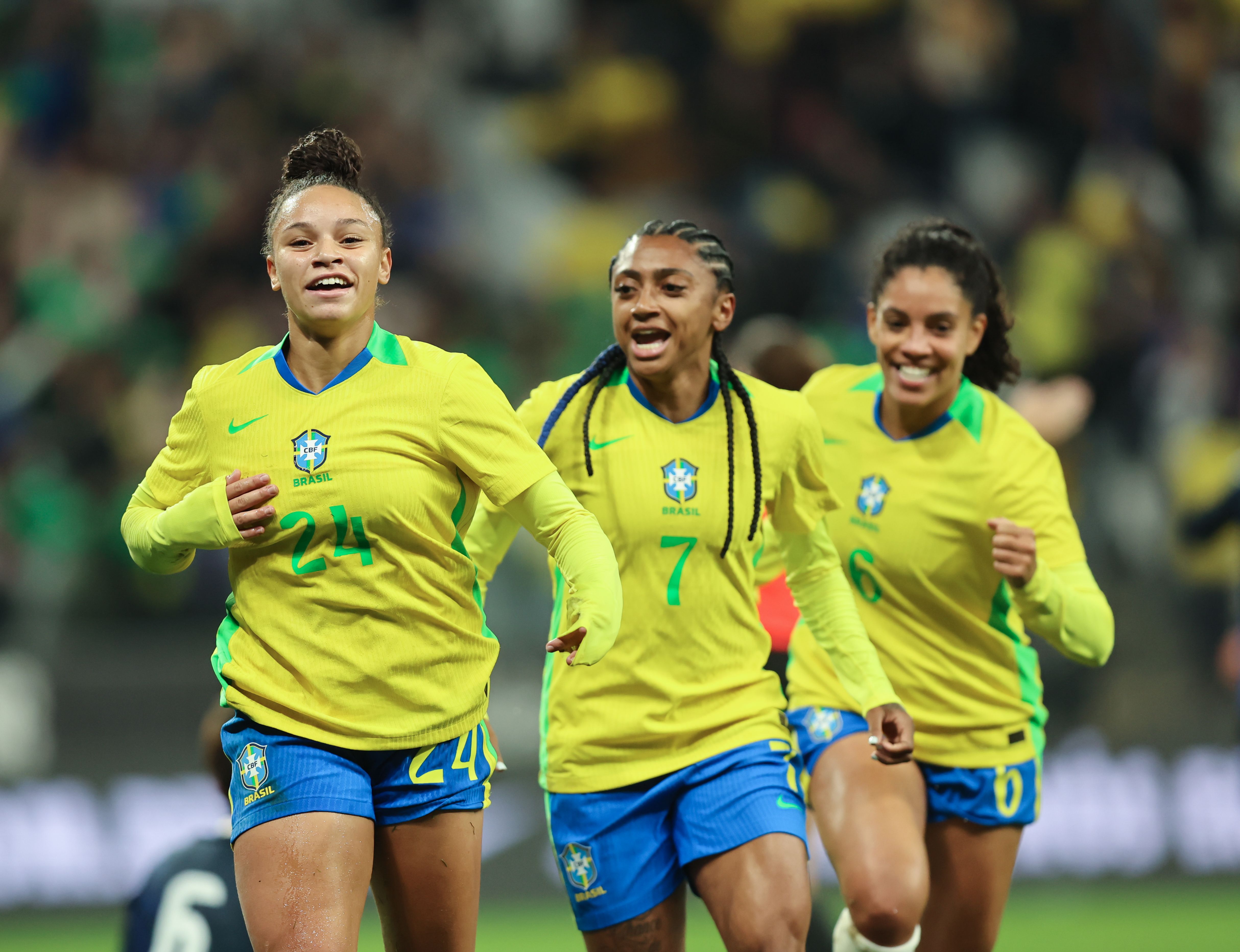 A imagem mostra Dudinha, Kerolin e Yasmim, em sequência da esquerda para a direita, de frente para a câmera comemorando o gol.