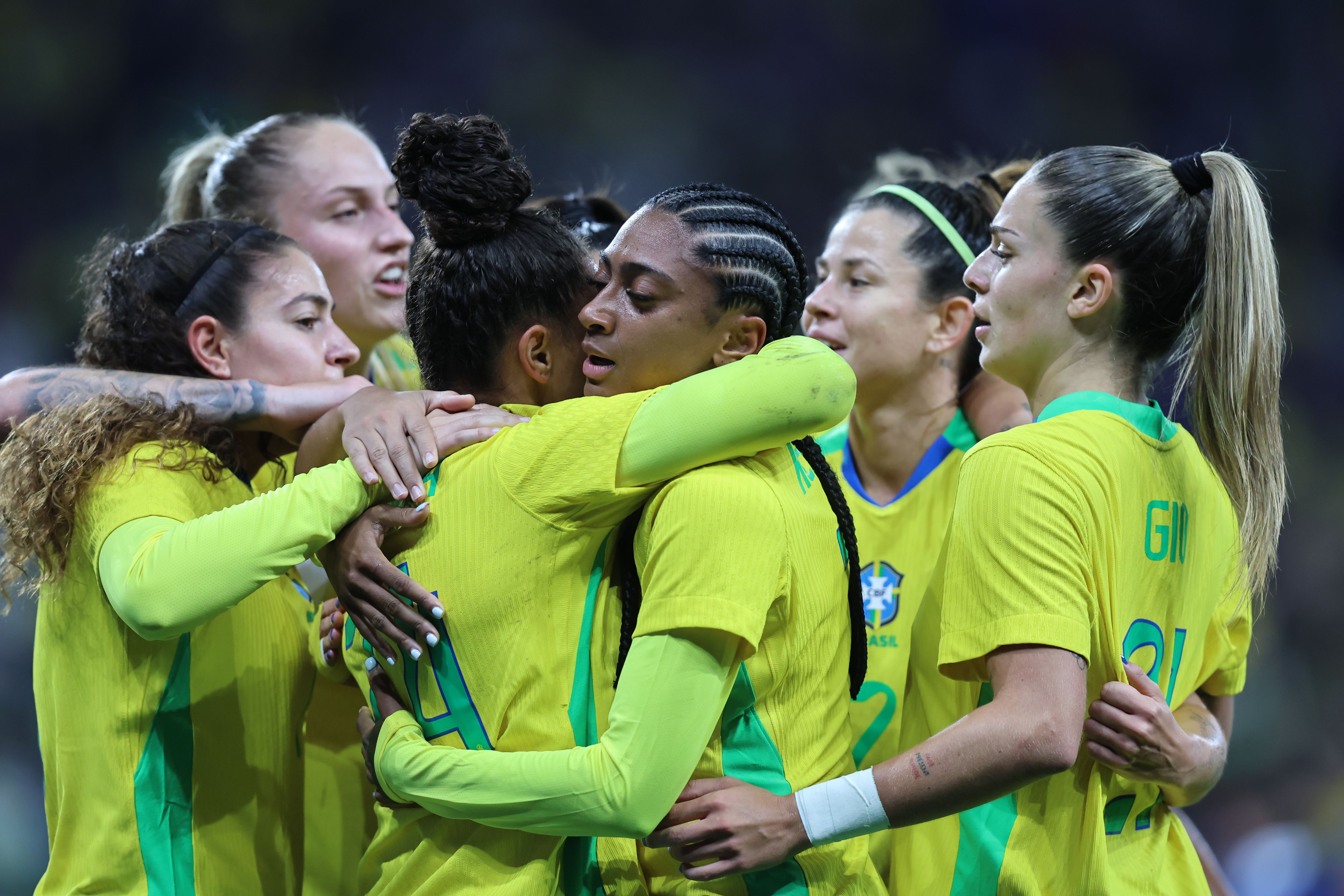 A imagem mostra, ao centro, Dudinha e Kerolin se abraçando. Em volta, há outras jogadoras do Brasil.