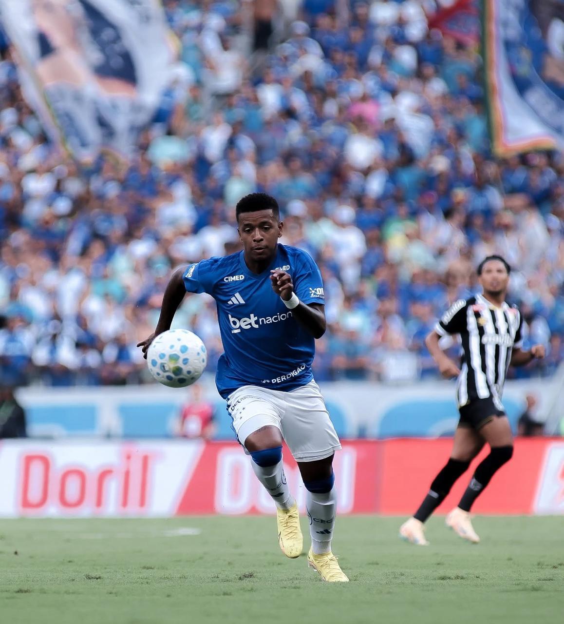 A imagem mostra o jogador Arroyo, do Cruzeiro, correndo com a bola.