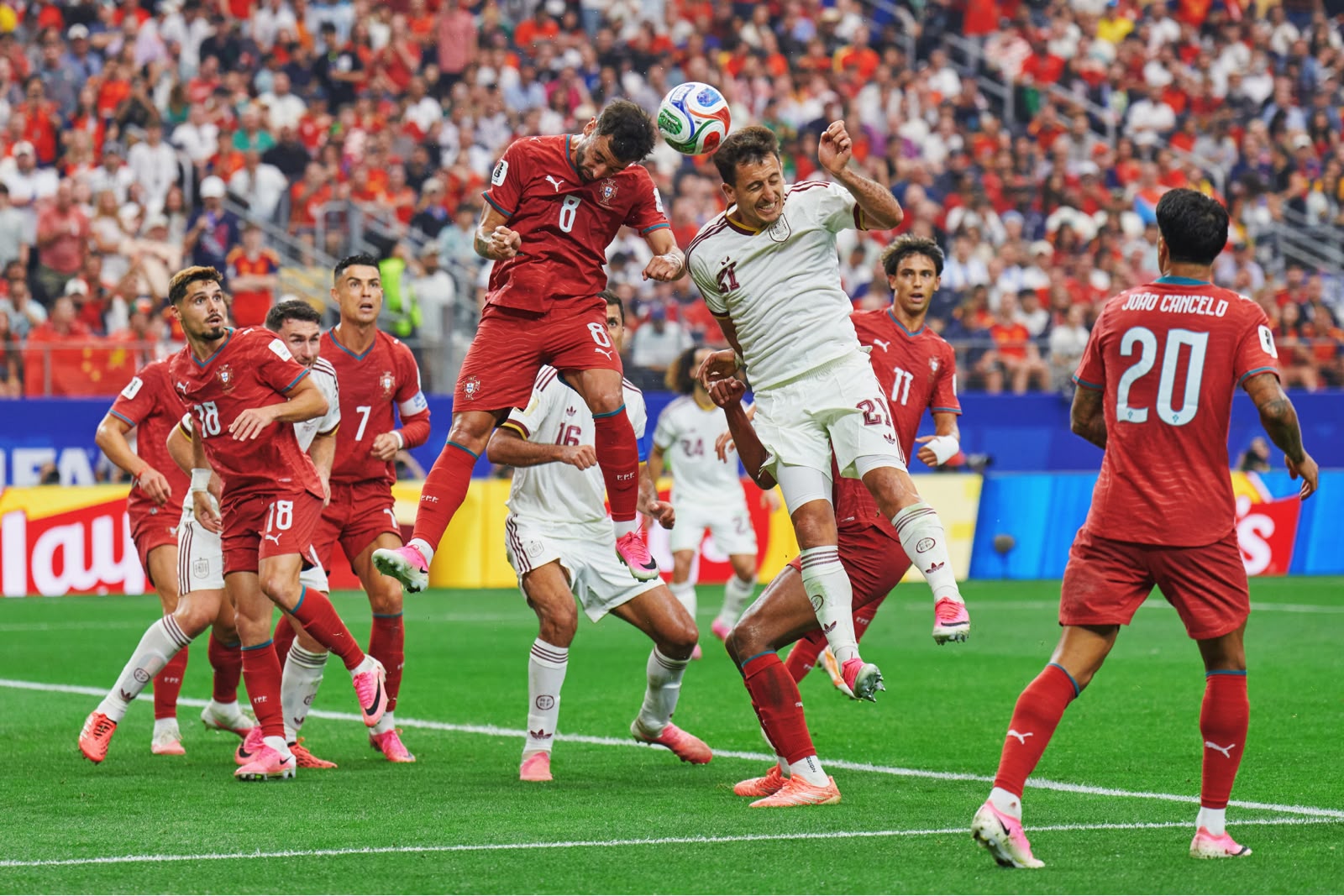 A imagem mostra uma disputa de bola aérea entre as equipes