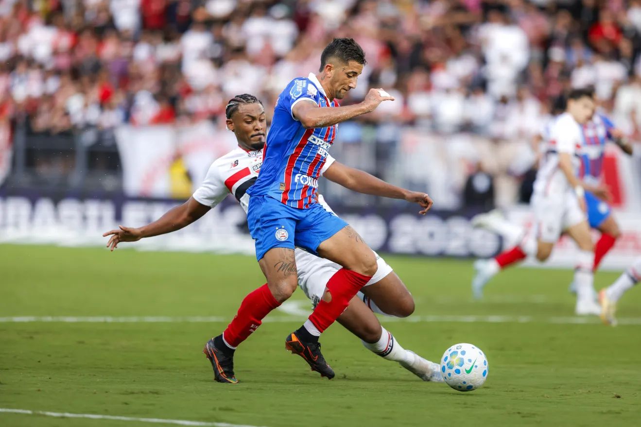 A imagem mostra um jogador do Bahia e um do São Paulo disputando a bola.
