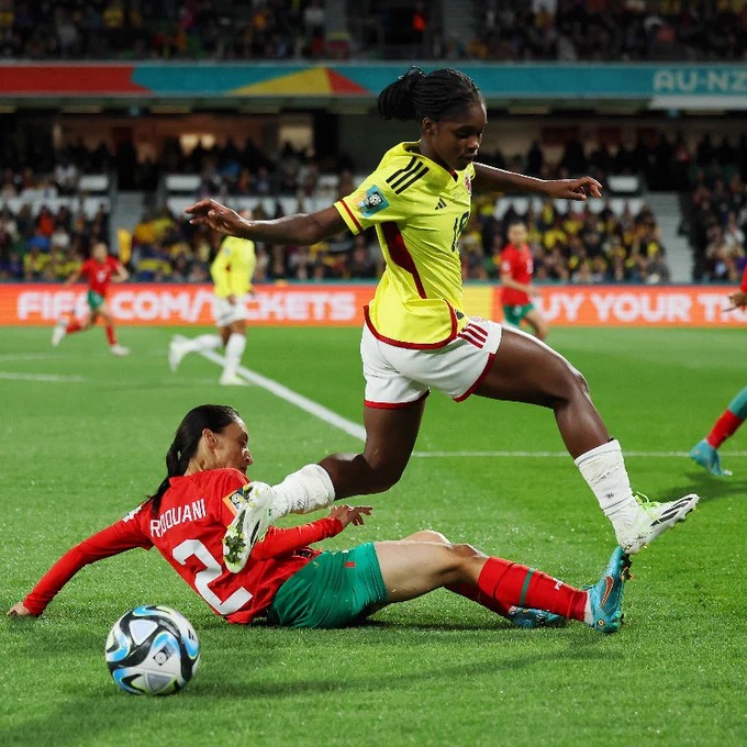 A colombiana, Linda Caicedo em pé, em disputa de bola com a marroquina Zineb Redouani, no chão.