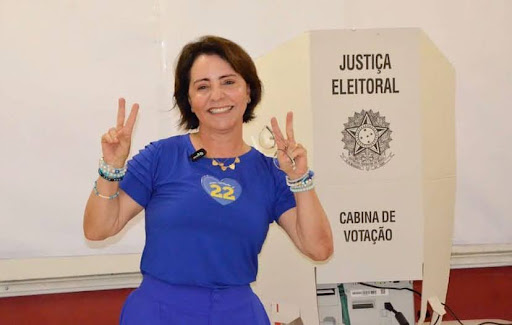 Emília Corrêa (PL) posando para foto ao lado da cabine de votação. 