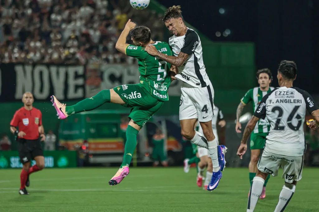 A imagem mostra João Pedro Tchoca, do Corinthians, disputando a bola no ar com Perotti, da Chapecoense.