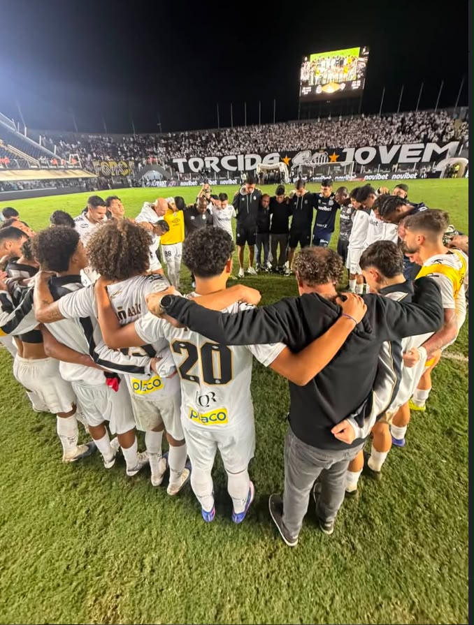 A imagem mostra o elenco do Santos em circulo de braços dados 