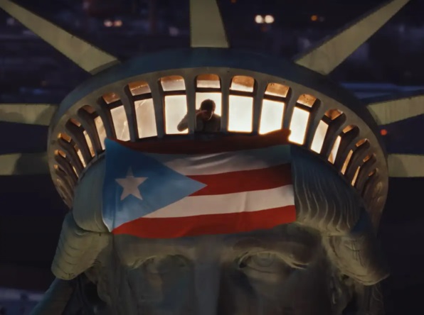 Bad Bunny em videoclipe de sua música "Nuevayol", no topo da Estátua da Liberdade, em Nova Iorque, com uma bandeira de Porto Rico hasteada sobre o monumento.