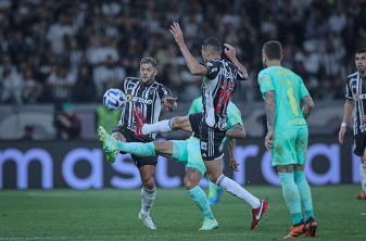 Três jogadores disputando a bola, dois do Clube Atlético Mineiro e um do Palmeiras. 