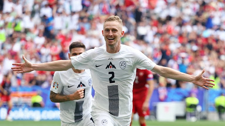 O jogador esloveno, Žan Karničnik, comemora gol da seleção de braços abertos olhando para a camêra.