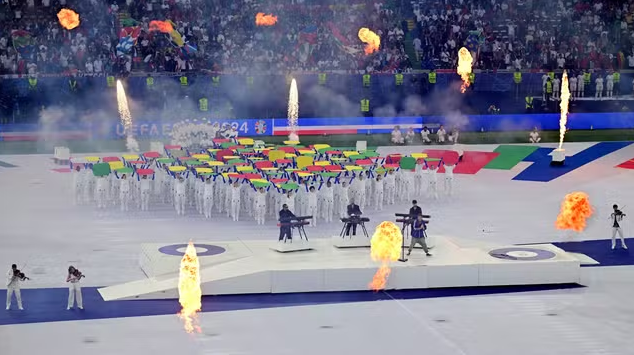 Cerimonia de abertura da Eurocopa 2024, no estádio olímpico de Berlim. Na foto, a festança conta com fogo, instrumentistas, cantores e uma performance teatral ao fundo.