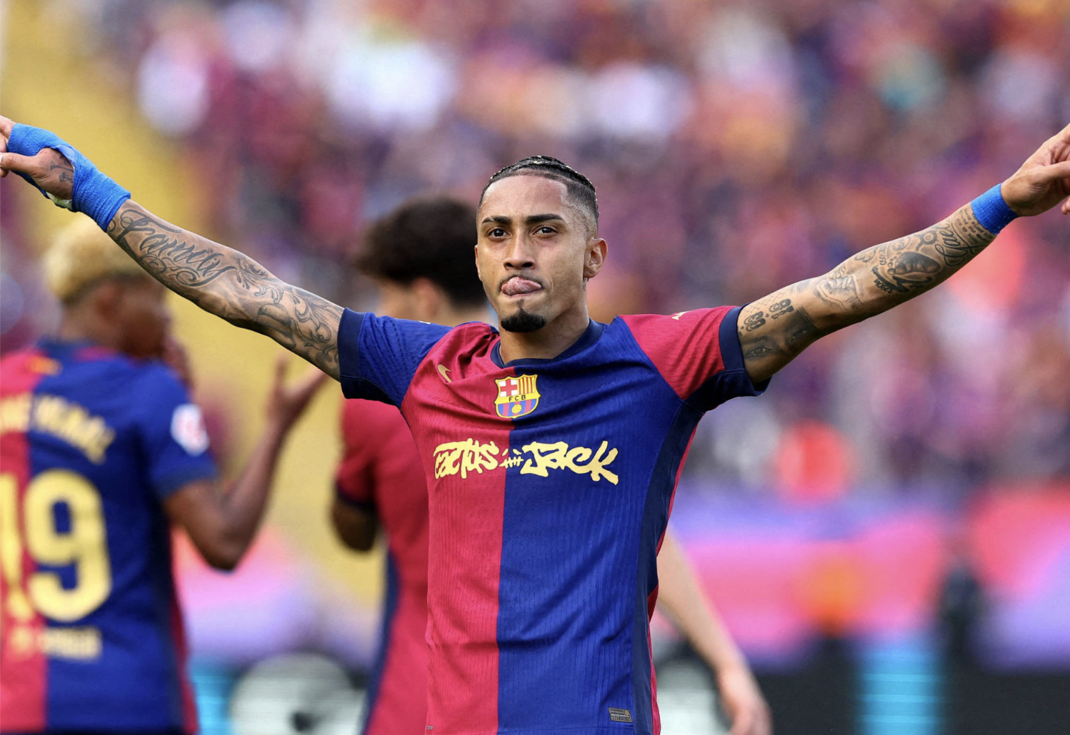 Raphinha, atacante brasileiro do Barcelona, comemorando gol com os braços levantados