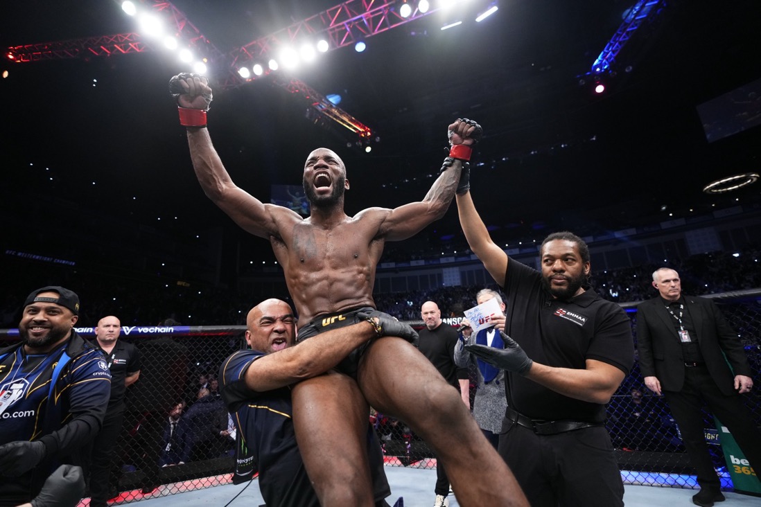 Leon Edwards comemora sua vitória enquanto é carregado pelo seu coach (Dave Lovell) e tem sua mão levantada pelo árbitro (Herb Dean). (Foto: Jeff Bottari | Crédito: Zuffa LLC via Getty Images | Reprodução: @UFC)