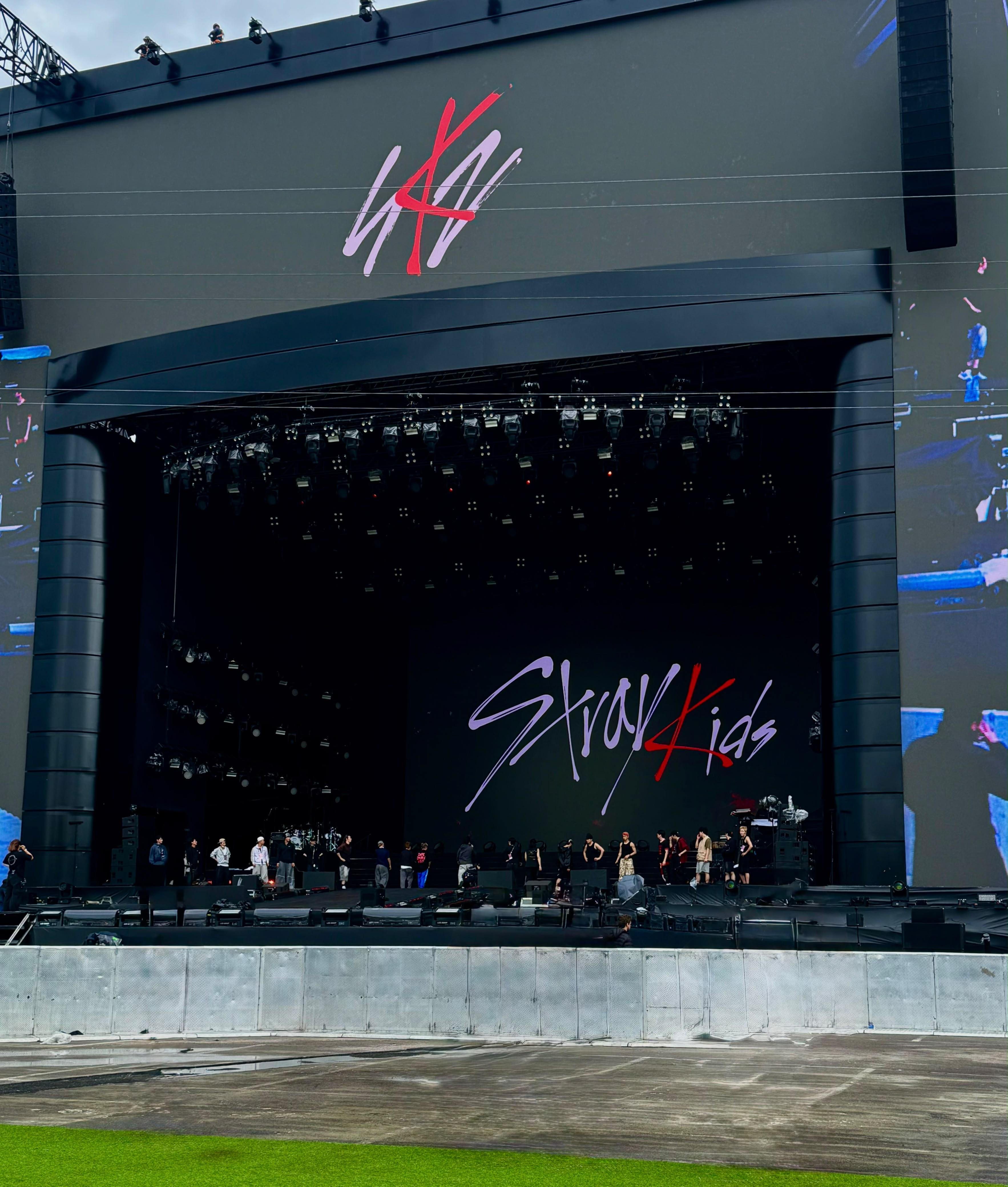 Palco de show dos Stray Kids em montagem, com o nome da banda exibido em um grande telão e área do público vazia à frente.