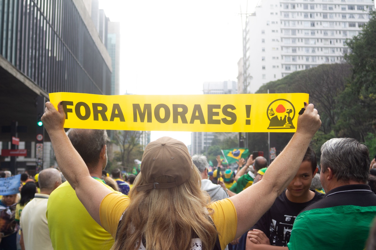 Mulher loira, em meio a multidão segura faixa "Fora Moraes!" no ato