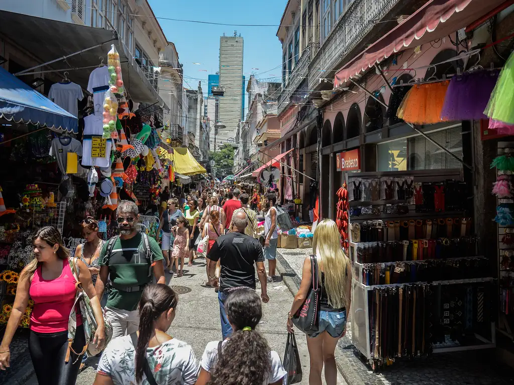 Grande quantidade de pessoas em uma rua com muitas lojas 