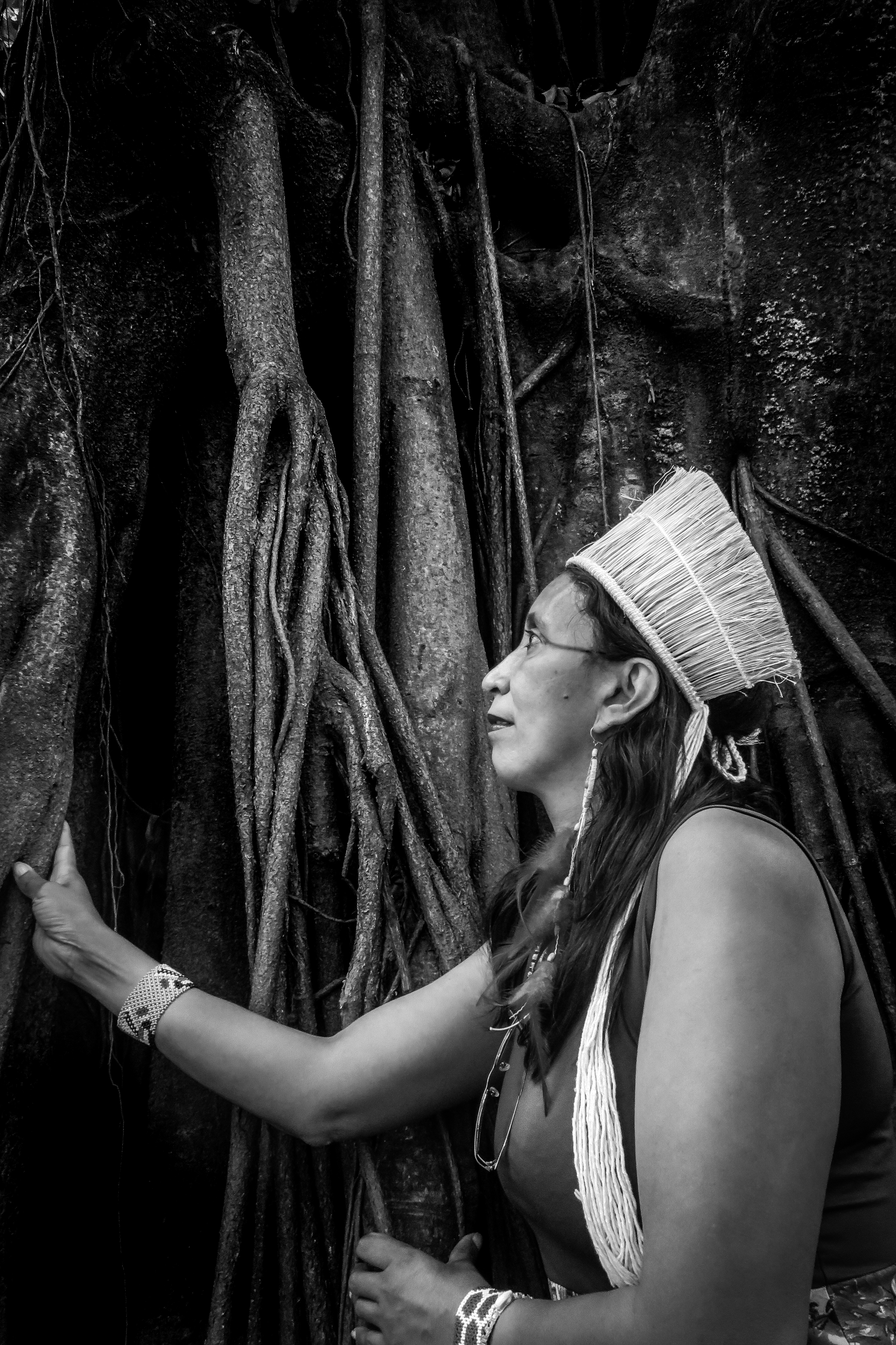 mulher indigena toca e contempla a árvore