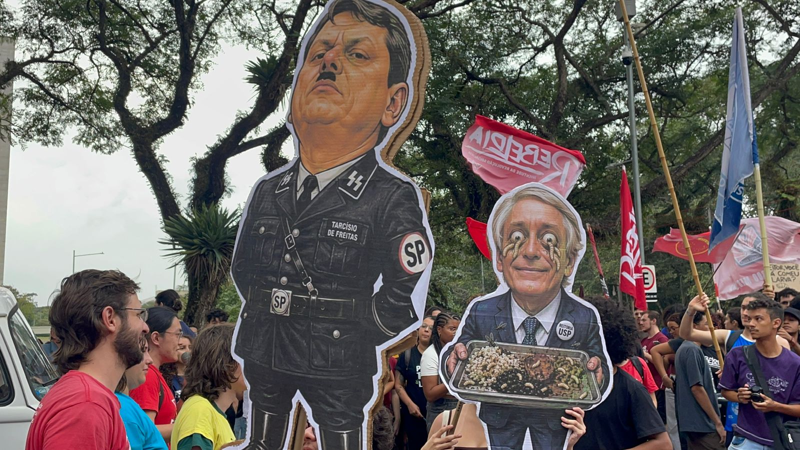Cartazes de caricaturas de Tarcísio de Freitas e Aluísio Augusto Segurado durante o ato em frente a reitoria do dia 28/05. Foto: Beatriz Foz.