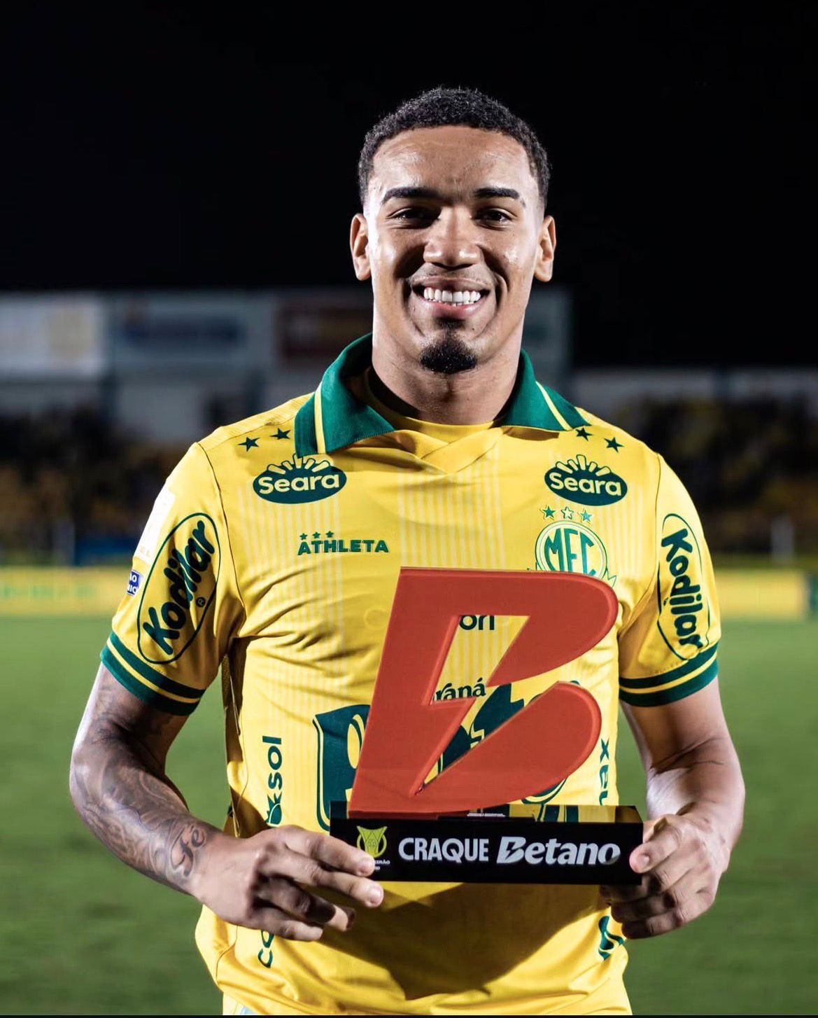 A imagem mostra Denilson, do Mirassol, com o troféu de melhor da partida. 