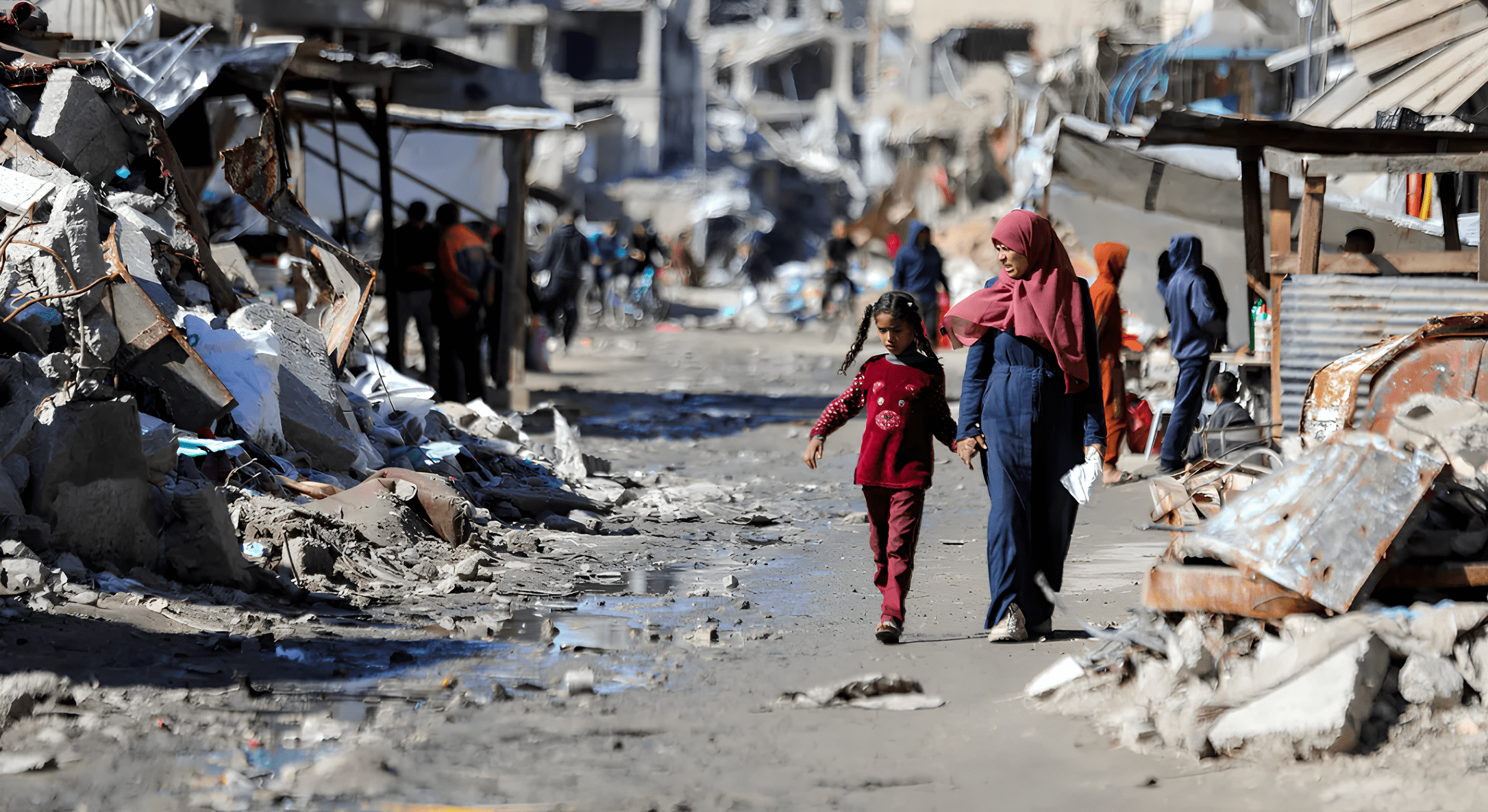 Mulher adulta e uma criança caminham de mãos dadas em meio a destroços. Foto: REUTERS/Dawoud Abu Alkas/CNN Conteúdo