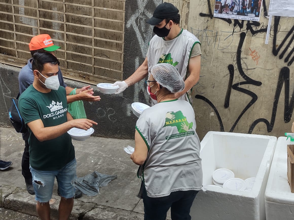 voluntários distribuindo refeições para outras pessoas na rua