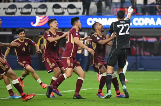 Jogadores Venezuelanos comemorando a defesa de pênalti do seu goleiro, jogadores de camisa vinho e goleiro de camisa preta. (Foto: Patrick T. Fallon/AFP)