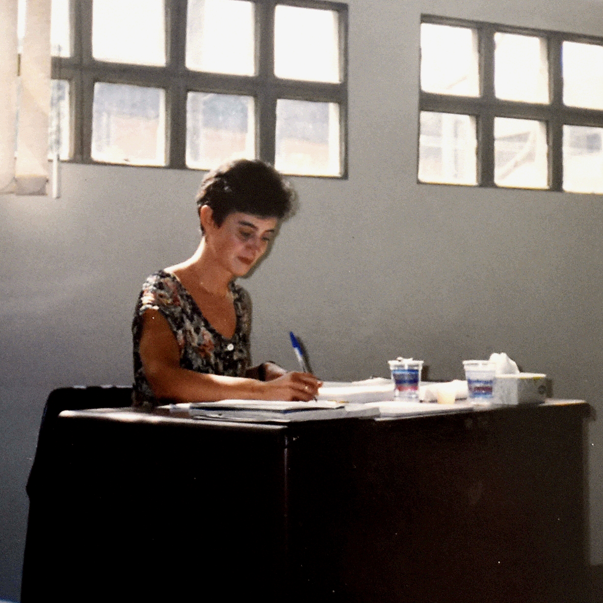 Isabel Marques, sentada em uma mesa escrevendo.