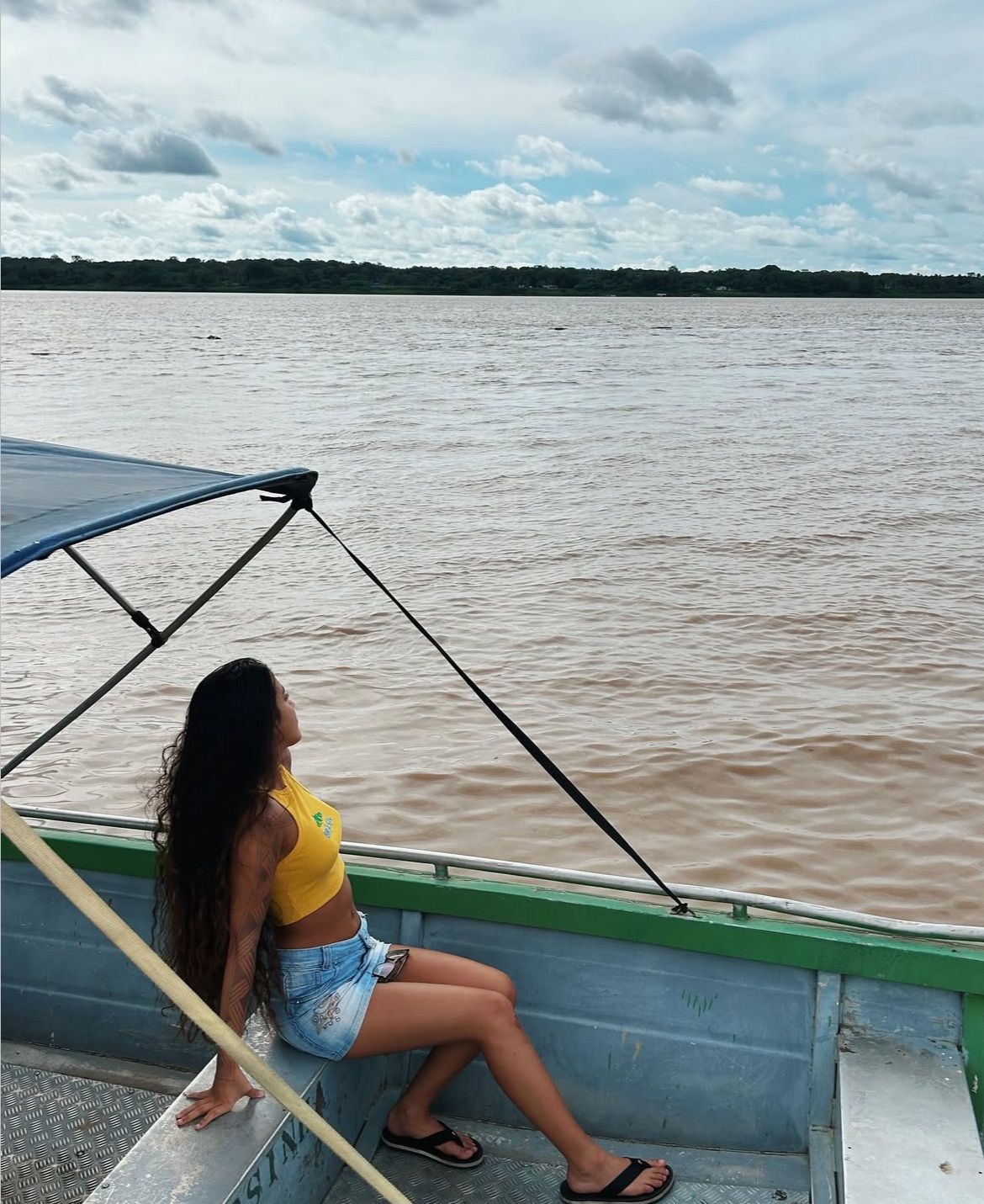 menina sentada em barco olhando ao longe pro rio