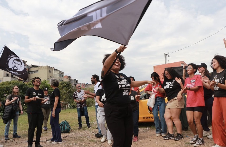 Samara Martins dançando com bandeira do Partido União Popular em meio a caminhada em campanha 