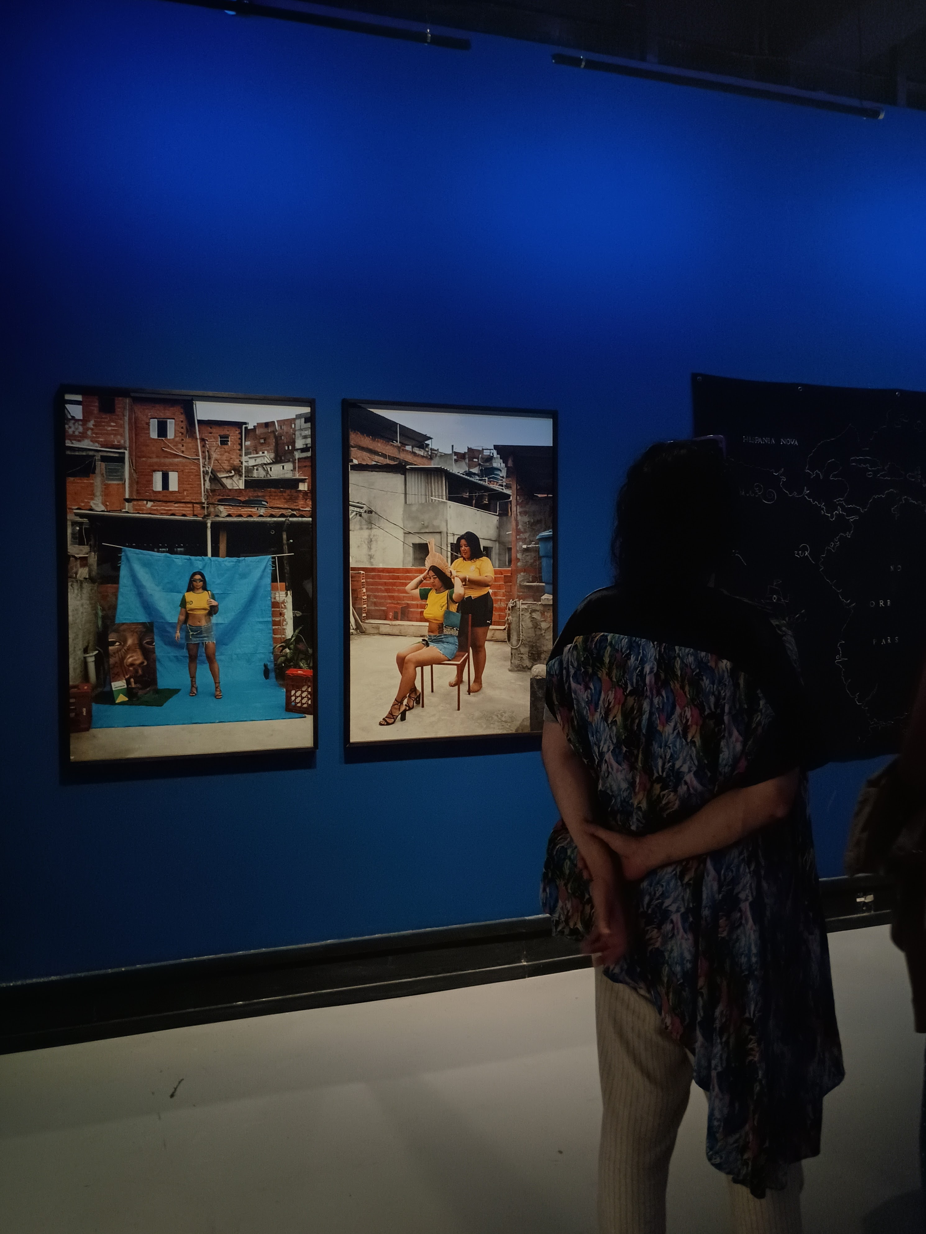 Homem à frente de fotos de mulher indígena na favela