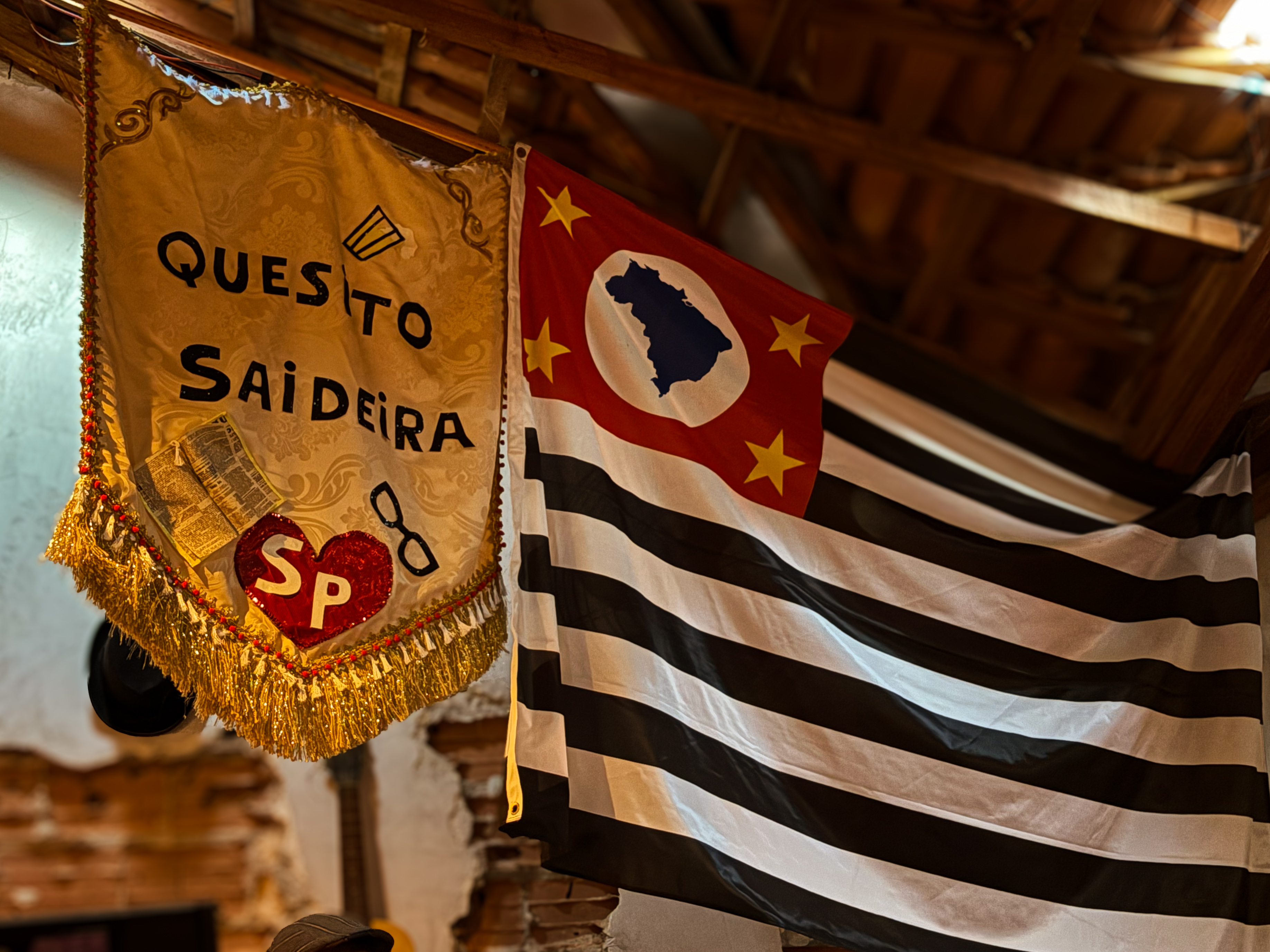 O estandarte personalizado do evento "Quesito Saideira" e a bandeira do estado de São Paulo, que decoram o cenário. Foto: Laura Celis