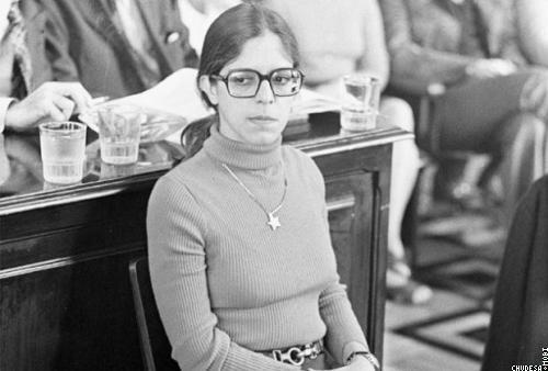 Foto em reto e branco de Inês Etienne sentada durante julgamento olhando pro lado