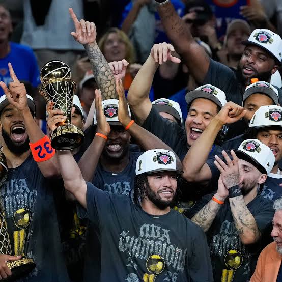 Na imagem contém o jogador Jalen Brunson, segurando o prêmio de melhor jogador das finais da NBA.