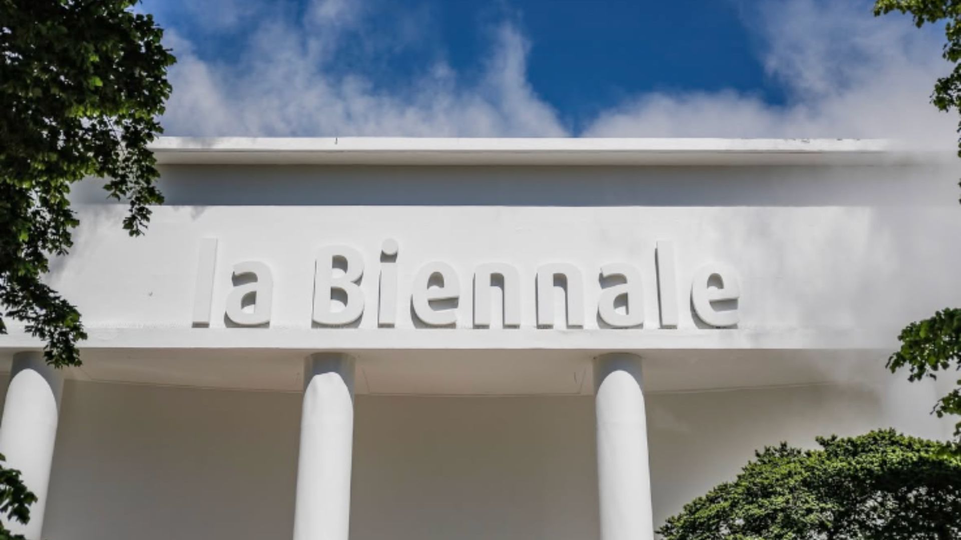 Fachada da Bienal de Veneza com folhas de árvores nas laterais